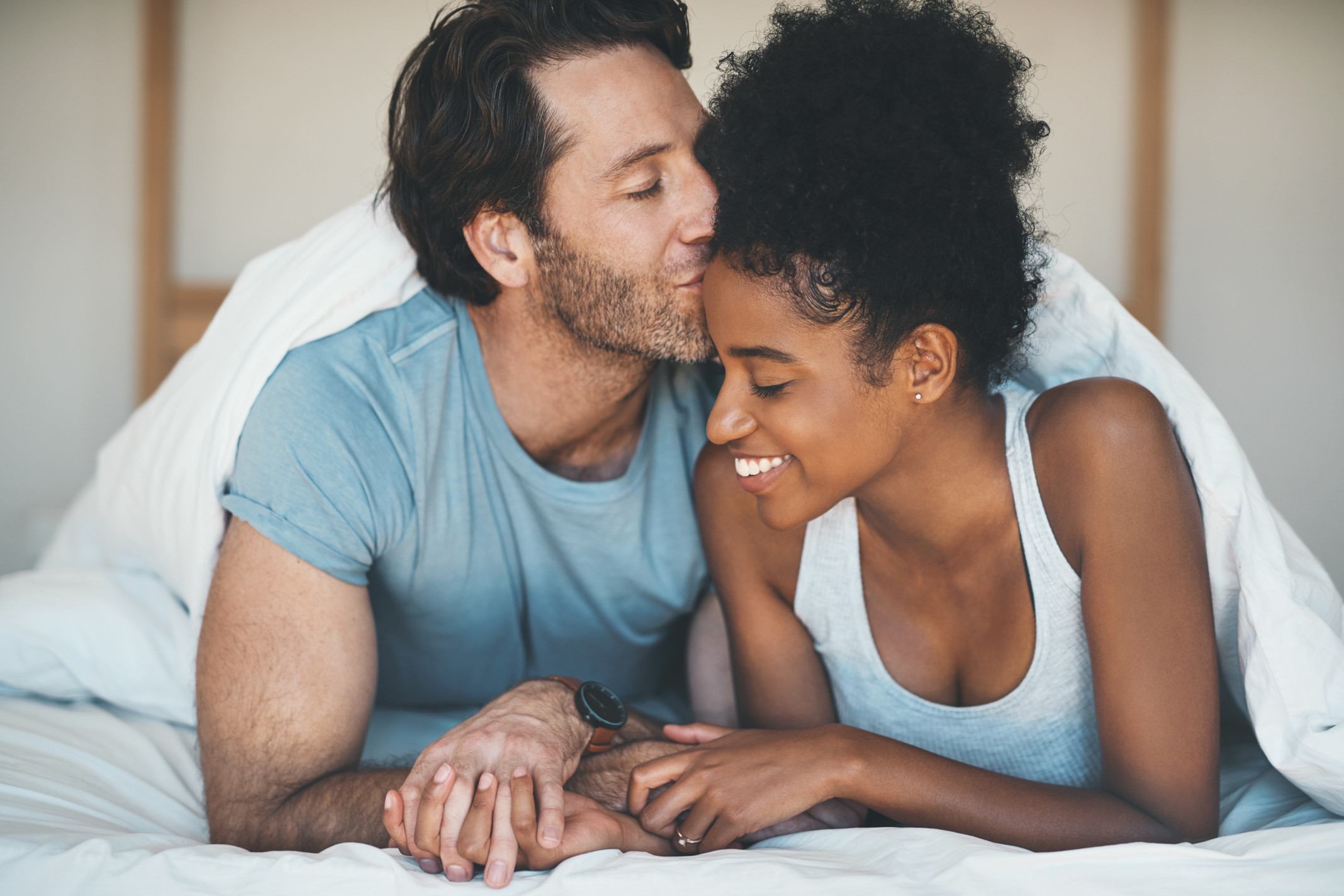 couple holding hands in bed