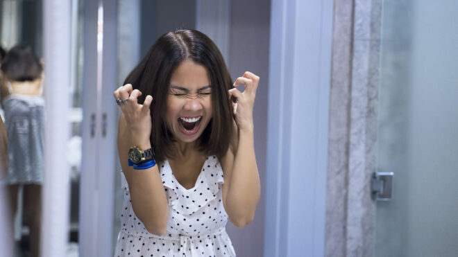 Angry woman shouting at mirror and crying