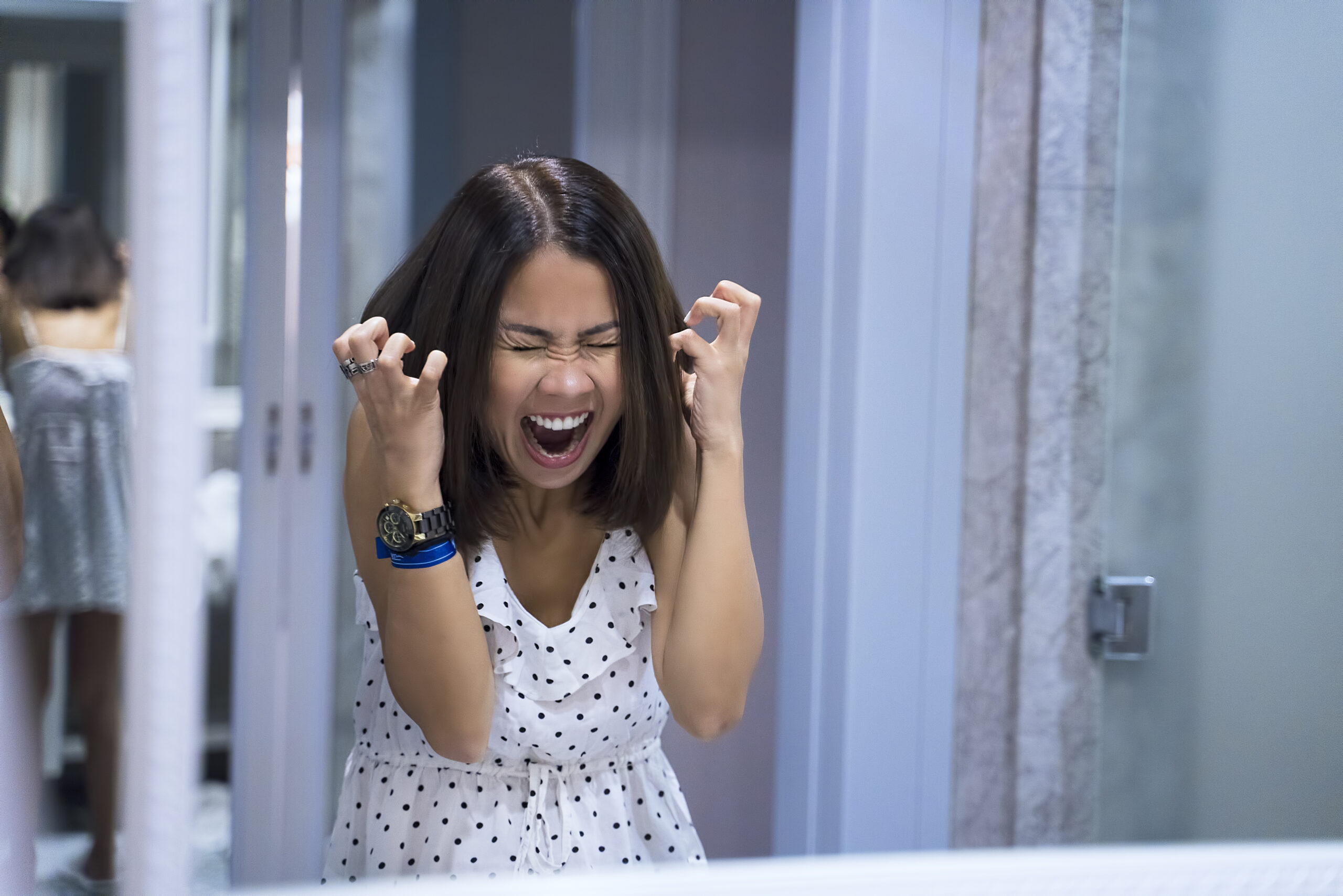 Angry woman shouting at mirror and crying