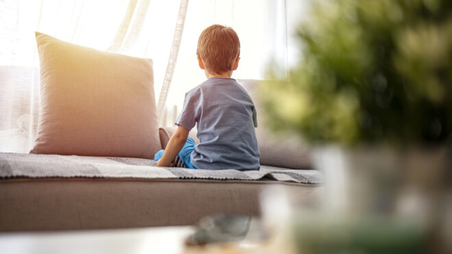 Toddler from back, looking trough the window.