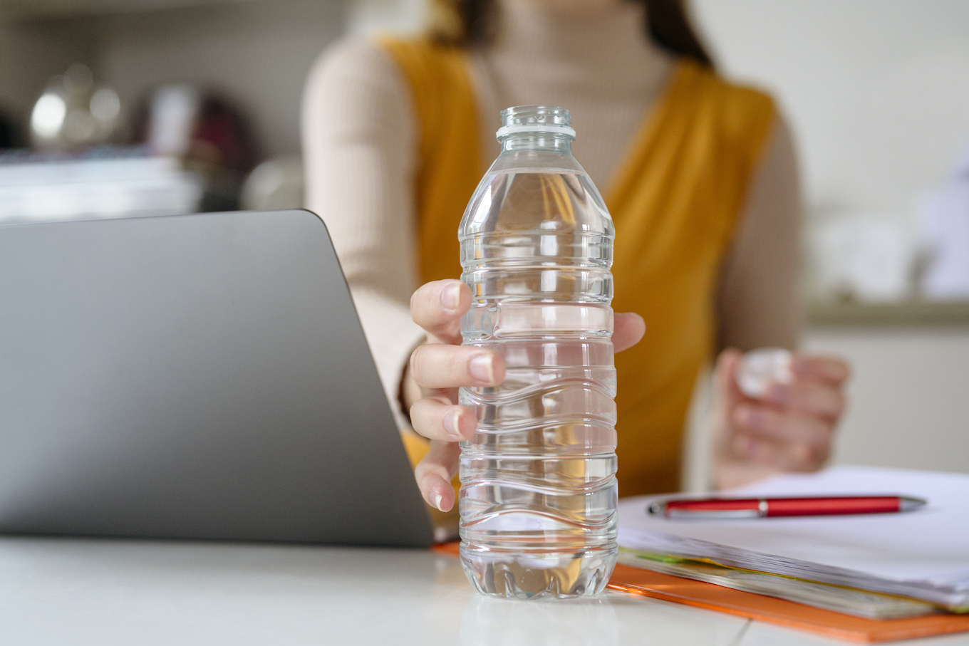 Young businesswoman reaching for water bottle in home office
