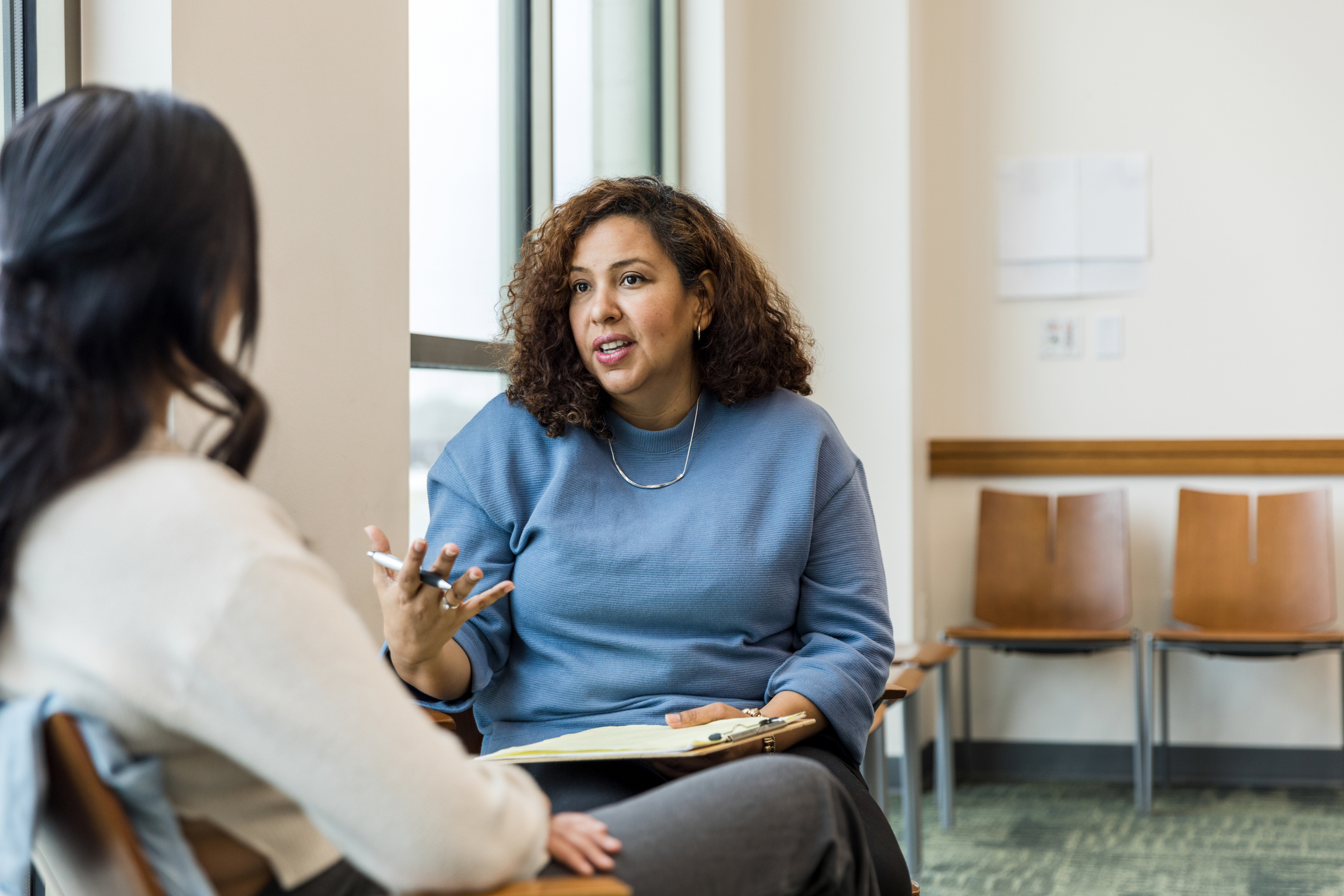 Female therapist gestures while talking with the unrecognizable woman