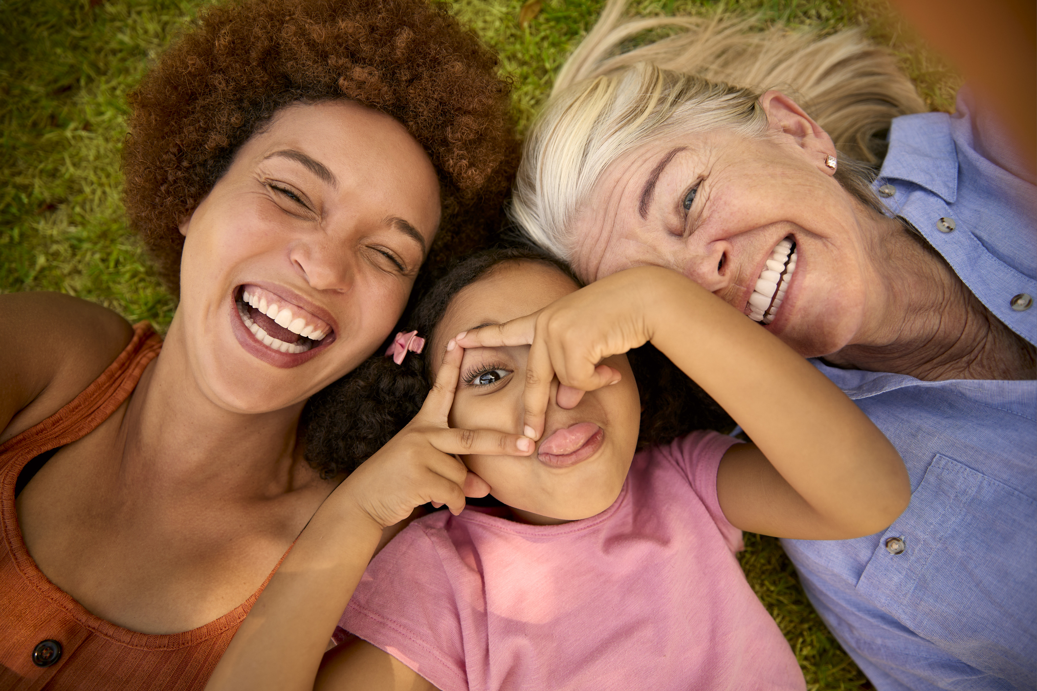 POV Overhead Shot Of Multi-Generation Female Family Lying On Grass Taking Selfie On Mobile Phone