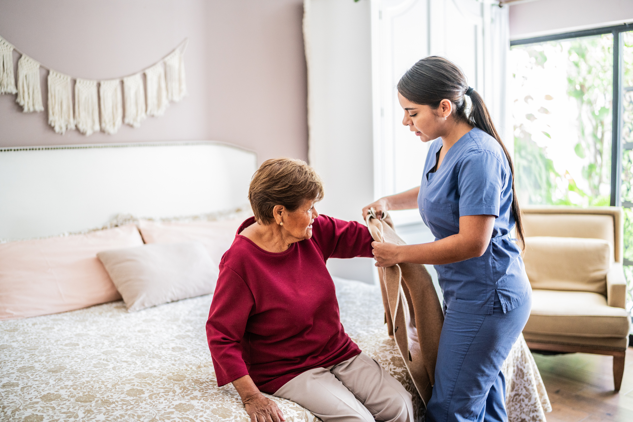 Home caregiver assisting a senior woman to get clothed in a nursing home
