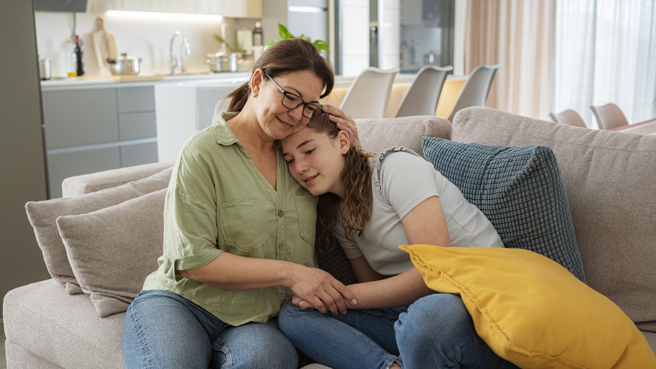 Loving mother and teenager daughter hugging on the sofa