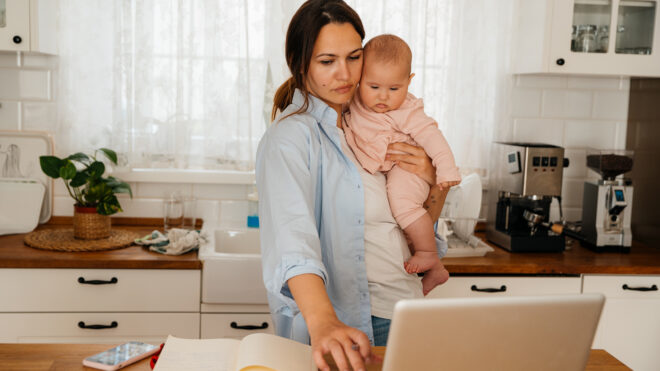 Mother talking on a phone and working from home while taking care of her new born baby girl