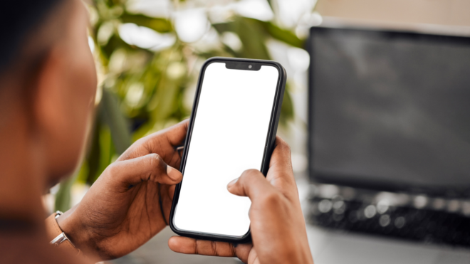 Black teen using phone with computer screen in the background
