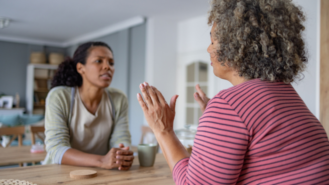 a Black woman looking frustrated while an older Black woman has her hands up in protest